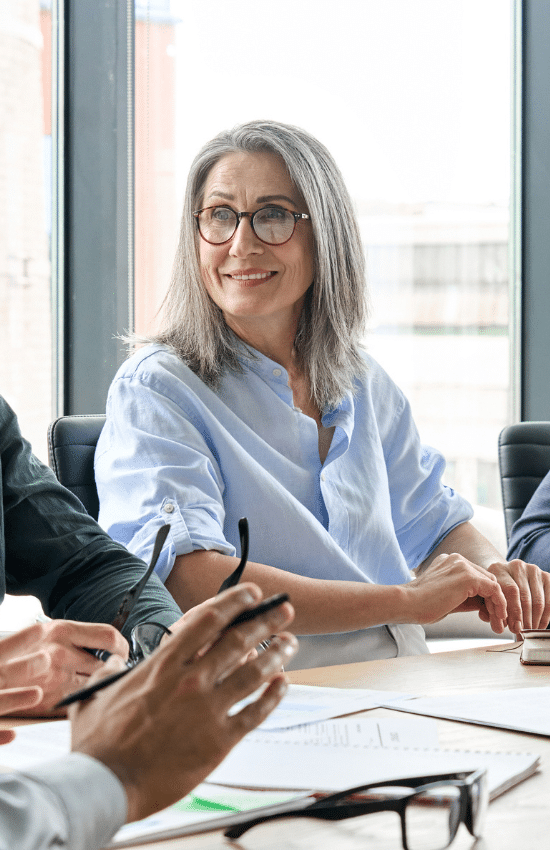 Seattle Executive Search Firm - Smiling senior Caucasian female businesswoman in glasses listening to male manager discussing corporation project at table. Corporate managers leaders working together in modern office.